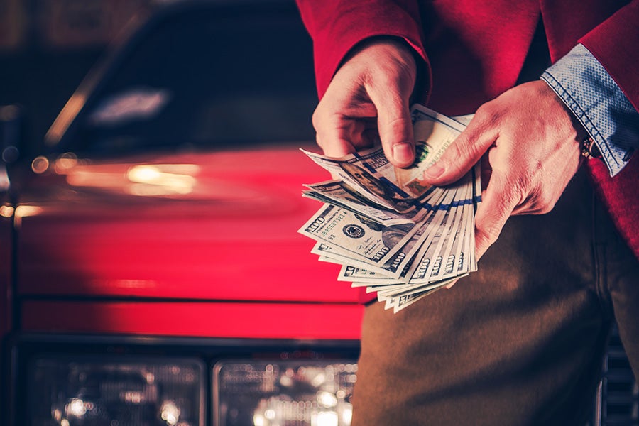 A customer holding cash and both hand after trading in a vehicle